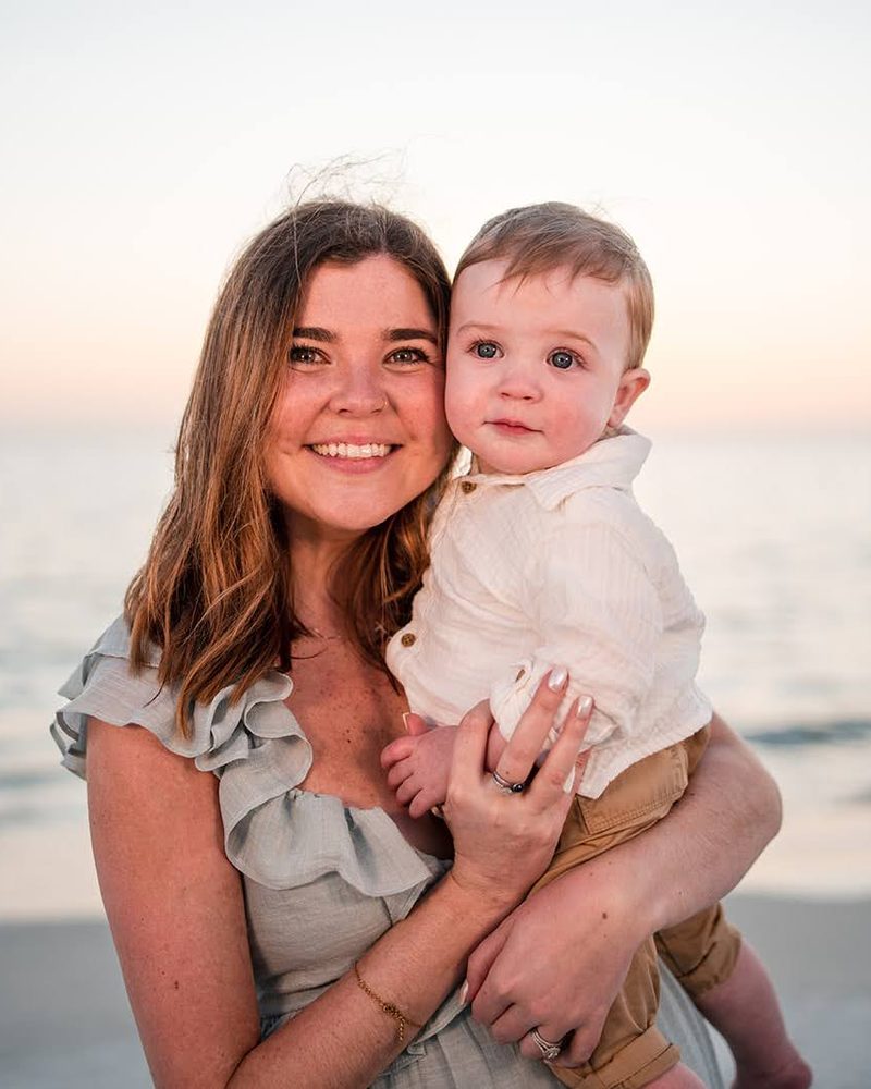 Mother holding her toddler son on the beach in soft pastel light just after sunset