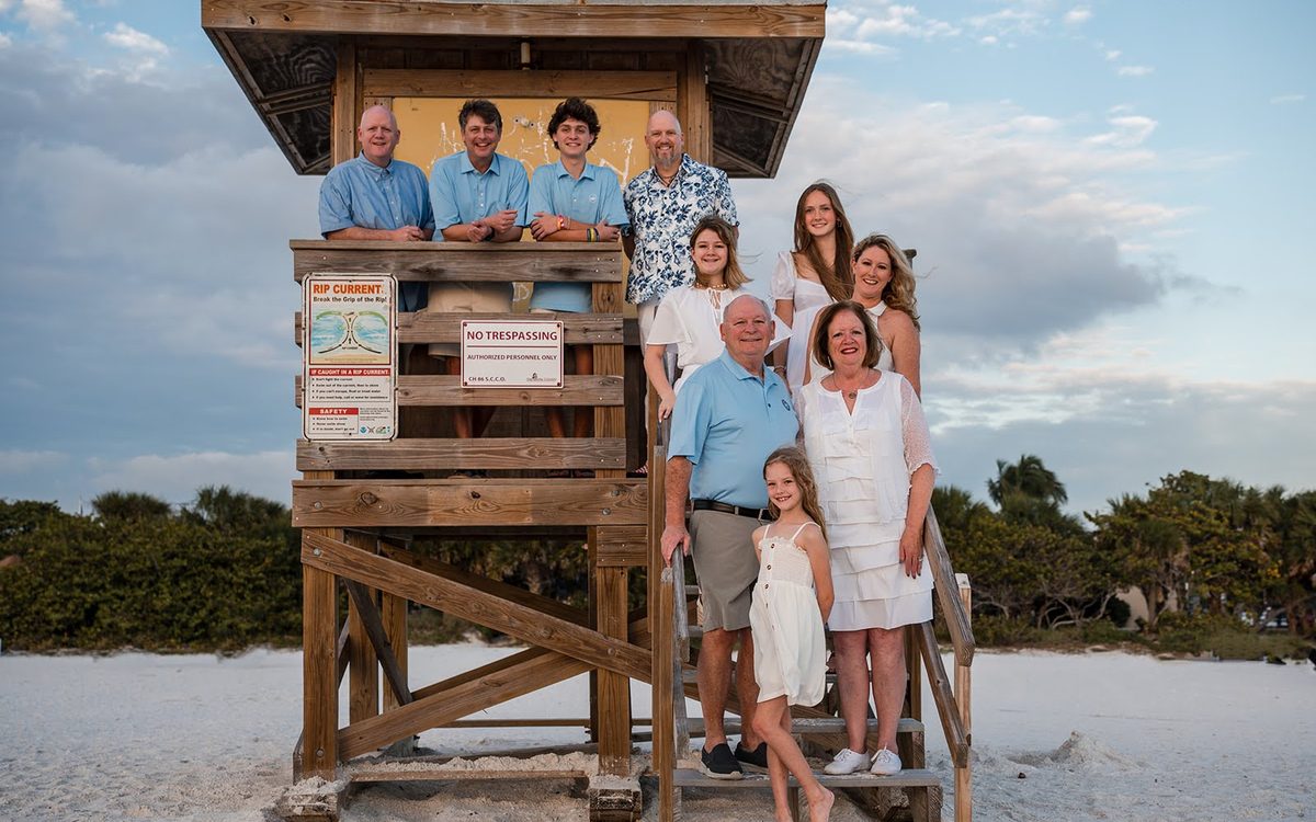 Large family posed on and around a wooden beach lifeguard stand at dusk