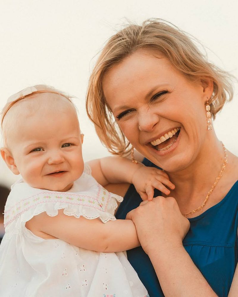 Mother laughing while holding her baby daughter during a beach family session