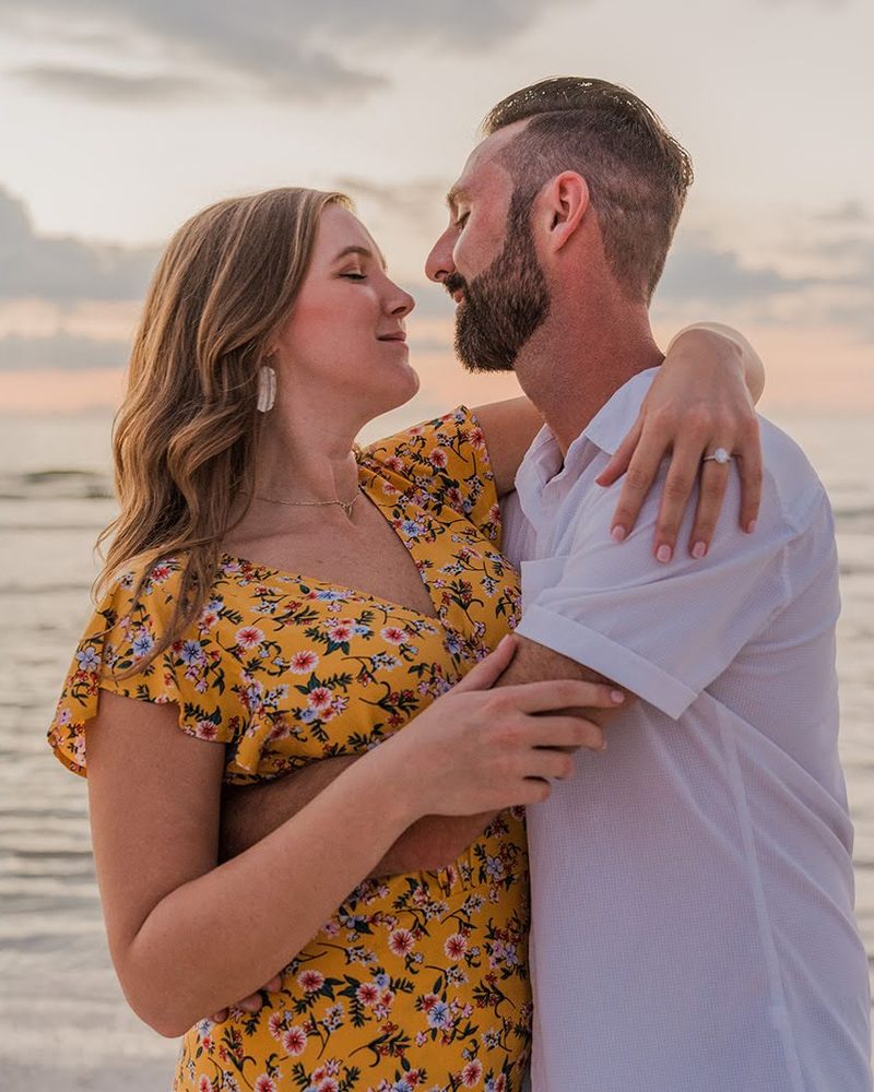 Couple about to kiss on the beach with a pink and grey sunset over the Gulf behind them