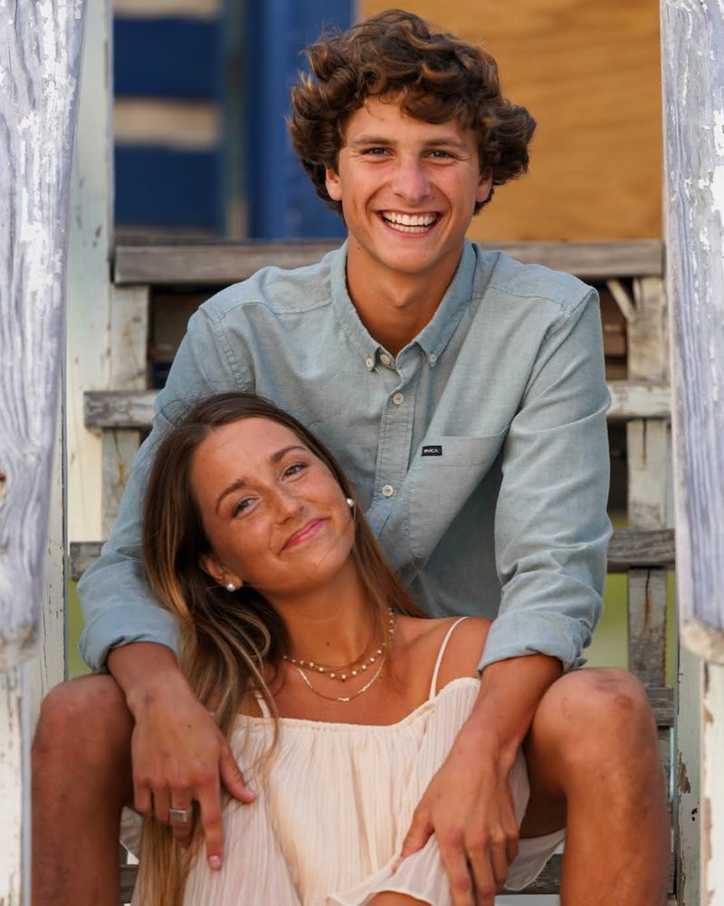 Young couple sitting together on weathered blue and white wooden beach steps
